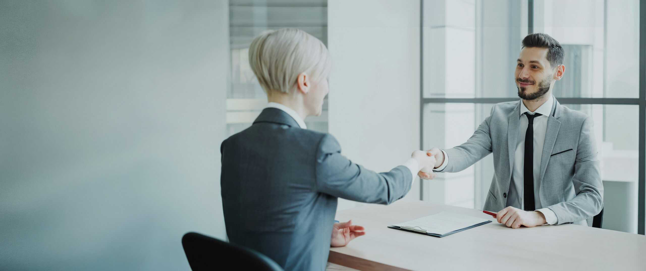Two professionals shaking hands across a table