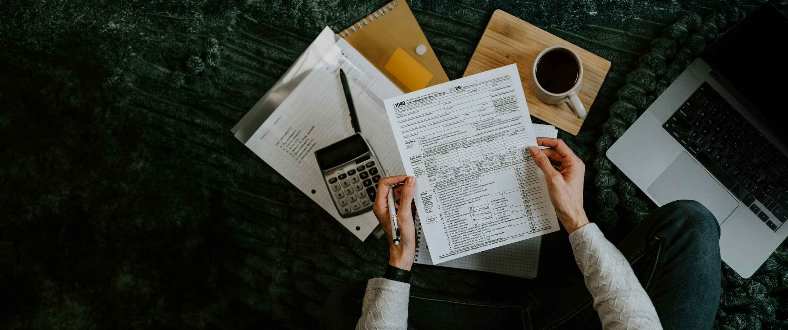 Reviewing loan documents with a calculator and laptop